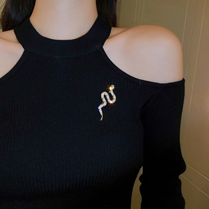 Close-up of sparkling zircon snake brooch pinned on black sweater fabric