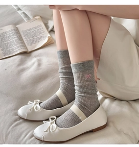 Detail of grey knitted cotton crew socks with pink bow embroidery and ballet flats