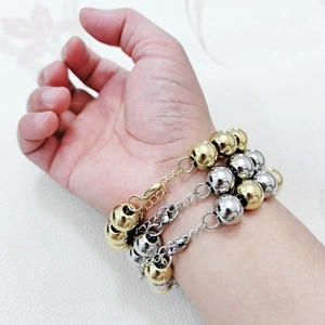 Detailed view of thick stainless steel beaded bracelets in gold and silver finish