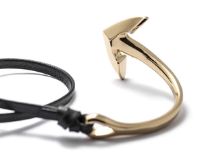 Close-up of golden anchor hook fastener with multi-layer black leather braided rope