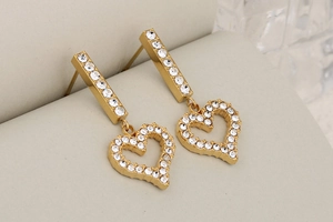 Detailed macro view of gold heart tassel earrings with sparkling pavé crystal accents