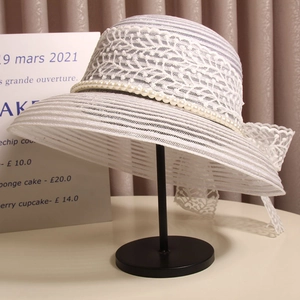 Détail d'un chapeau de soleil en dentelle blanche avec perles et grand noeud élégant