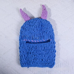 Close-up of blue knitted Halloween balaclava with purple horns and horizontal opening