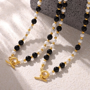 Elegant beaded necklace with black onyx and white shell, featuring golden OT toggle clasp