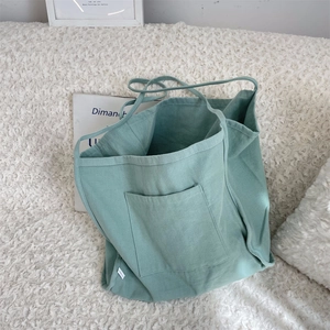 Close-up of mint green canvas tote bag showing the front pocket and textured fabric