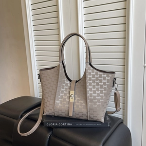 Chic khaki tote bag with monogram print and adjustable strap on a book background