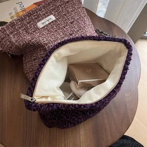 Close-up of woven tweed makeup bag with zipper showing interior cosmetics storage