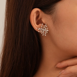 Detail shot of a silver snowflake earring with zircons and pearls on a model's ear