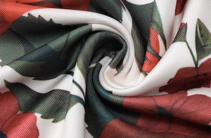 Detailed macro view of soft white floral fabric with red flowers and green leaves pattern