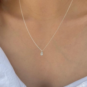 Close-up of minimalist 925 sterling silver necklace with light blue teardrop zircon pendant