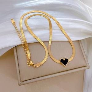 Detailed close-up of a golden snake chain necklace with a black heart pendant and clasp