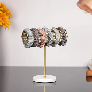 Morandi satin hair scrunchies set on golden metal stand with white marble base