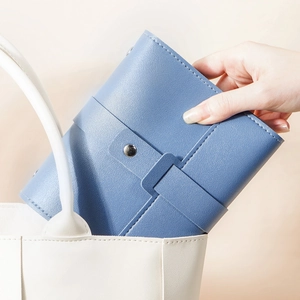 Blue faux leather jewelry organizer bag being placed in a white tote for travel