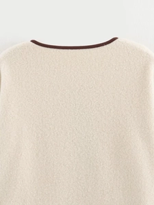 Dettaglio del colletto in pile beige con bordatura in pelle marrone a contrasto