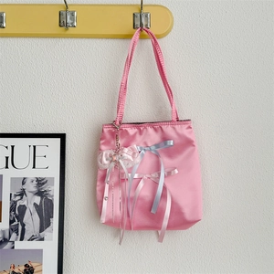 Detail of pink satin handbag featuring silk bows and decorative pearl chain pendant