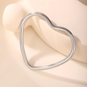 Macro view of polished silver heart-shaped bangle with minimalist cutout metal design