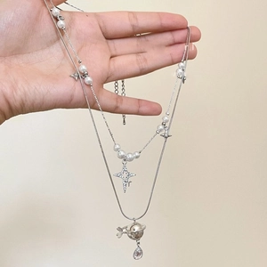 Double-layered pearl necklace with star and Saturn pendant featuring teardrop crystal
