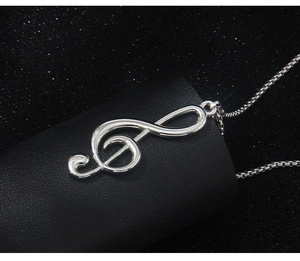 Macro shot of silver music note pendant on a chain over a textured black background