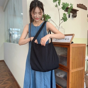 Détail de la texture d'un grand sac bandoulière en toile noire avec un motif gaufré bulles