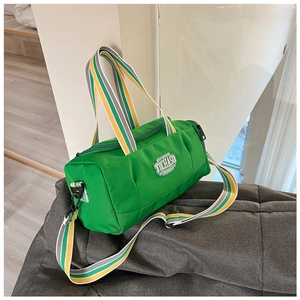 Macro shot of green nylon cylinder sports bag with colorful striped handles and logo patch