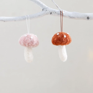 Ornamenti a fungo fatti a mano in feltro di lana rosa e marrone appesi a rami decorativi
