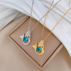 Close-up of gold and silver mermaid necklaces with blue sapphire-like gemstones