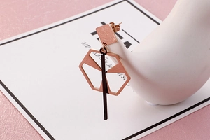 Rose gold geometric drop earrings on a swan jewelry stand with minimalist modern design
