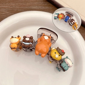 Detail view of cartoon bear and cat ornaments on a translucent brown claw hair clip