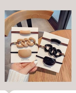 Detailed close-up of neutral beige and black elastic hair bands with resin geometric accents