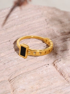 Detailed macro view of gold chain ring with black rectangular inlay on pink stone