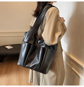 Detail of a large black PU leather tote bag with a practical front pocket for daily commute