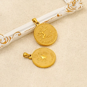 Makroaufnahme goldener 18K Sternzeichen-Anhänger für Schütze und Krebs auf Stoff