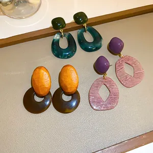 Detail of geometric resin and wood earrings in vintage blue, orange and purple tones