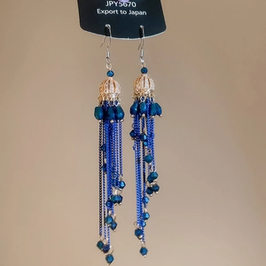 Detail view of gold boho tassel earrings with deep blue beads and long chain fringe