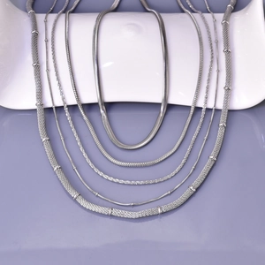 Detail view of five types of silver stainless steel chains on white ceramic display stand