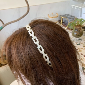 Detail of white acetate chain headband with rectangular links on brown hair