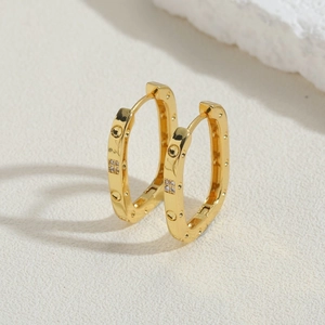 Detailed macro view of 18K gold-plated U-shaped earrings with tiny cubic zirconia stones