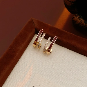 Détail de boucles d'oreilles dorées à double rangée avec émail bordeaux et zircons brillants