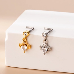 Macro detail of heart-shaped nose studs with wings in gold and silver stainless steel