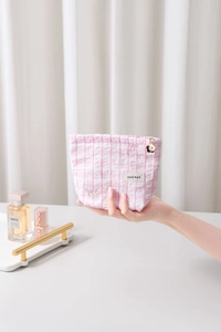 Détail de la trousse de maquillage à carreaux roses avec fermeture éclair fleurie dorée