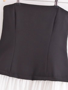 Detail of a black and white strapless midi dress featuring neat stitching and fabric texture
