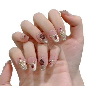 Uñas postizas de lujo estilo francés con piedras rojas, perlas y detalles dorados brillo