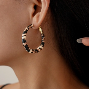 Close-up of leopard print leather wrapped hoop earrings on a model in vintage style