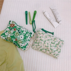 Detailed view of green floral cotton coin purses with zip closures and hair clips