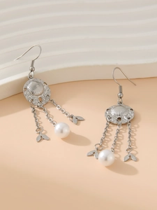 Detail of silver tassel earrings featuring shell motifs, delicate chains and pearls