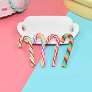 Miniature colorful polymer clay candy canes for DIY crafts on a white ceramic tray