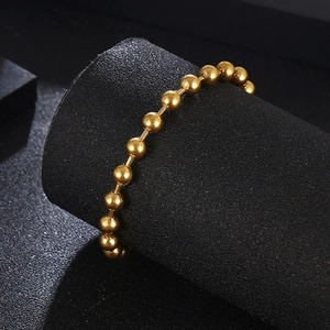 Hip hop titanium steel golden beaded bracelet for men and women on a dark jewelry stand