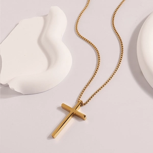 Detail shot of a minimalist gold stainless steel cross pendant with a classic box chain