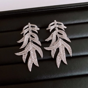 Macro shot of silver leaf tassel earrings with sparkling crystals on black tray