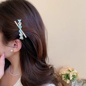 Détail d'une pince à cheveux plume en cristal bleu sur modèle avec perles